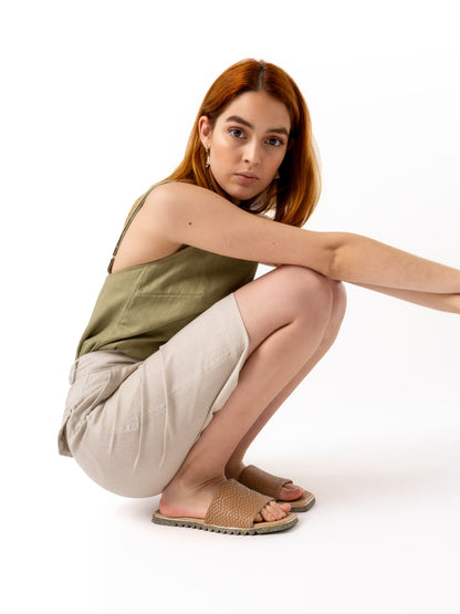 woman wearing olive green linen top and beige tailored shorts